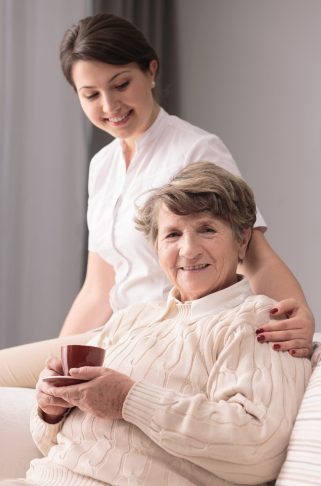 Young female caregiver taking care of older woman
